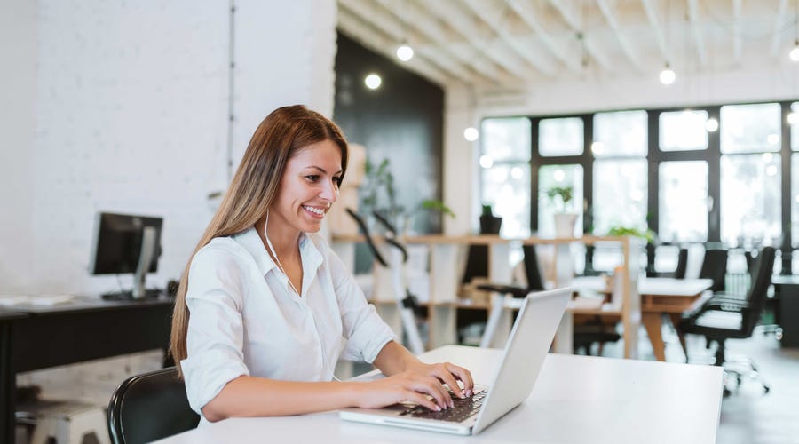 Mulher de fones no escritório aprendendo sobre educação corporativa.