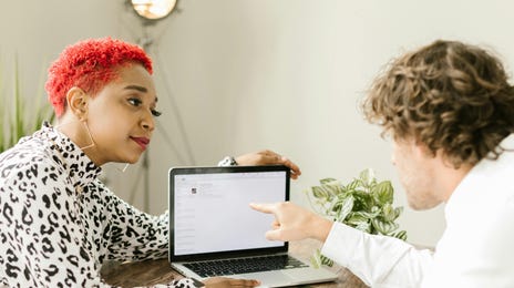 Mulher mostrando pedindo uma opinião sobre um projeto por meio de uma comunicação eficiente e um computador com slides.