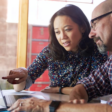 Mulher e homem debatendo juntos o que estão vendo em um laptop.