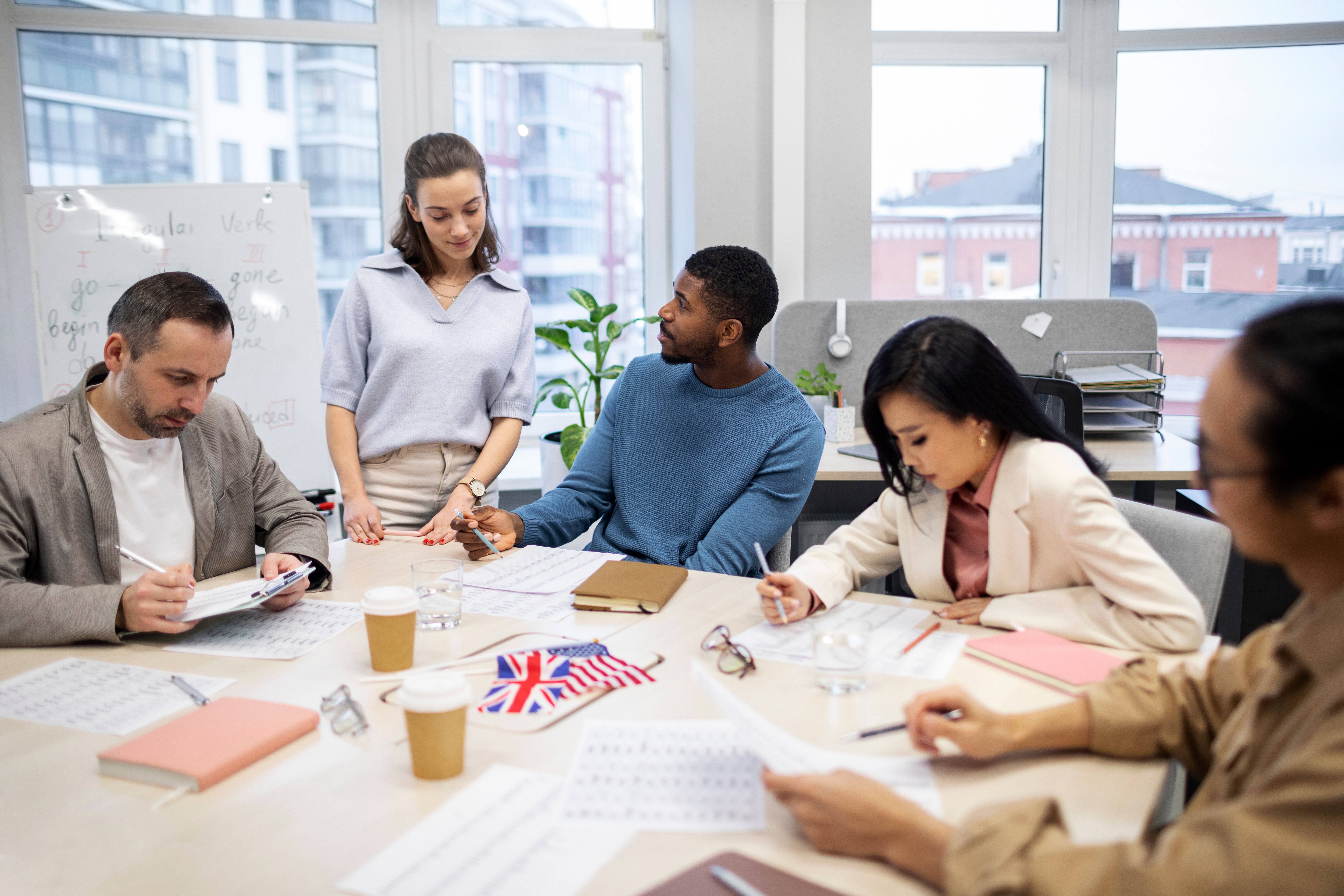 Grupo de tres pessoas realizando treinamento de idiomas no ambiente de trabalho