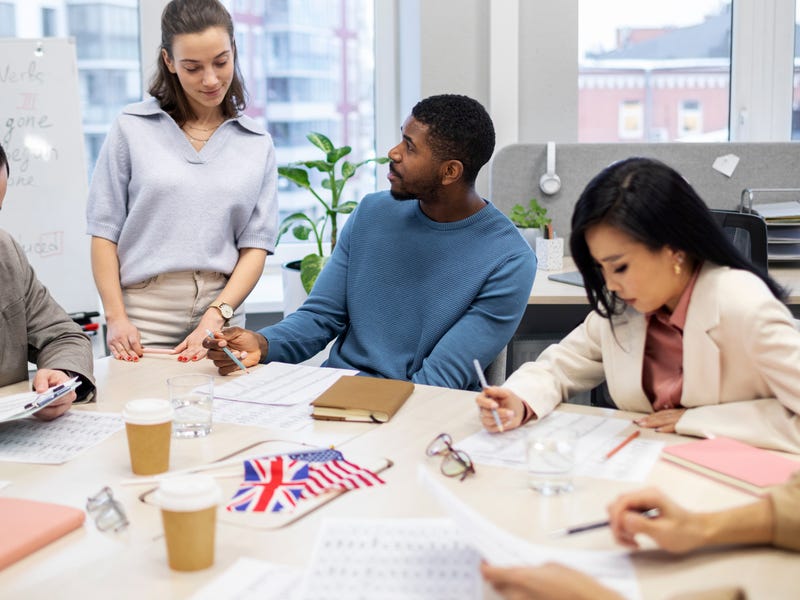 Grupo de tres pessoas realizando treinamento de idiomas no ambiente de trabalho