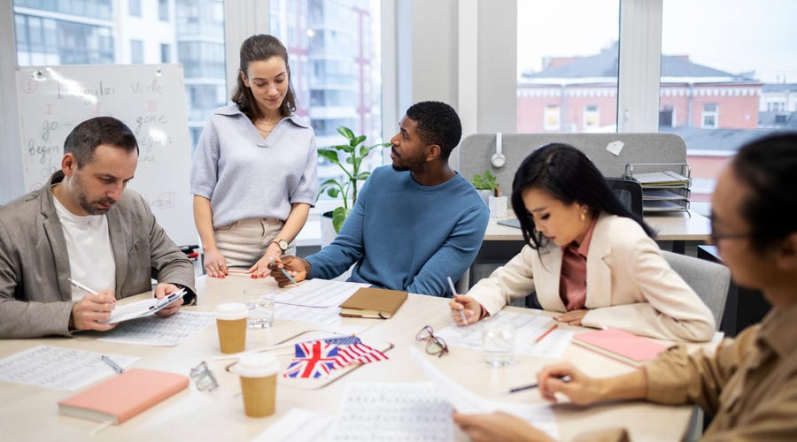 Grupo de tres pessoas realizando treinamento de idiomas no ambiente de trabalho
