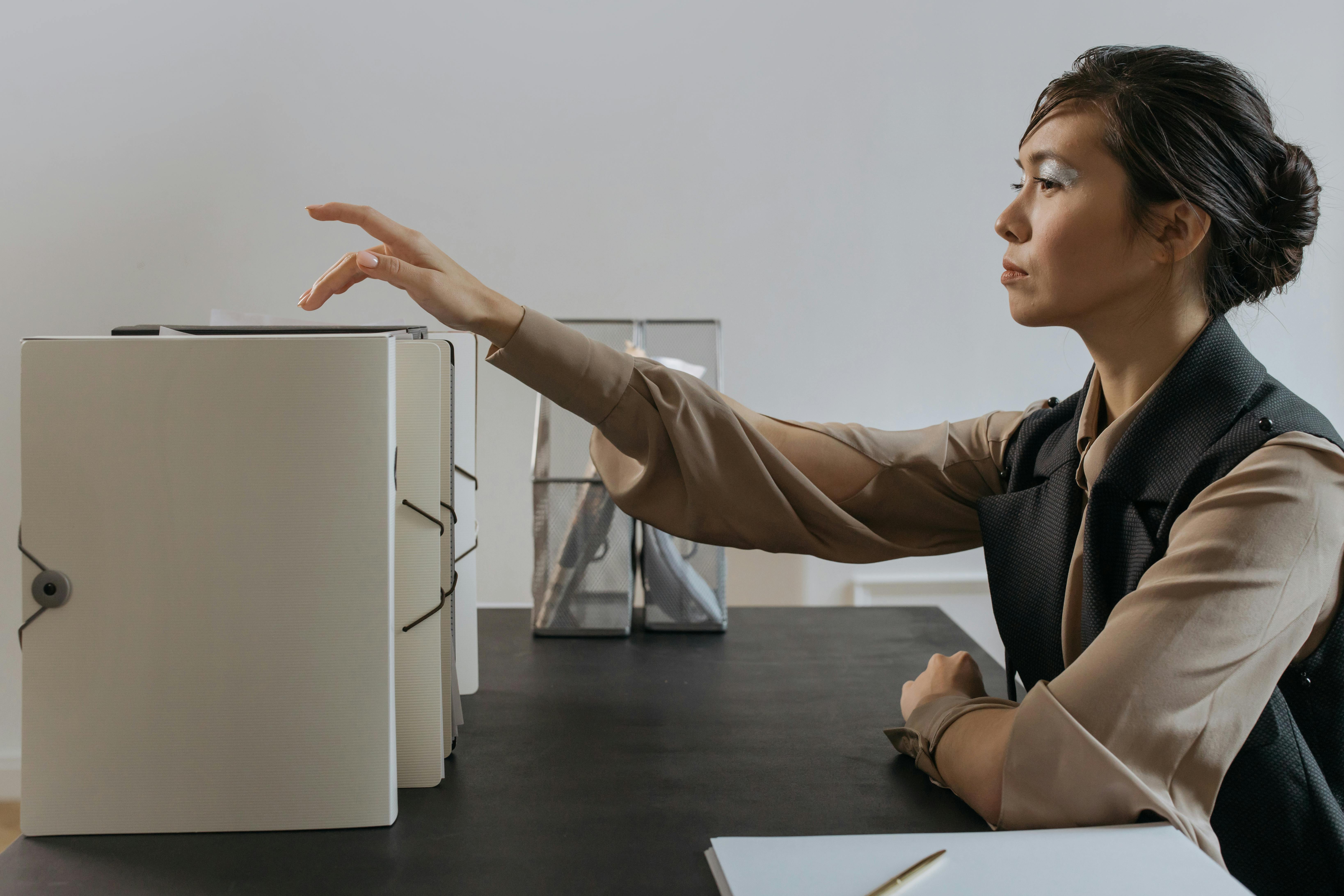 Mulher com expressão séria está organizando documentos em pastas após treinamento de cultura de responsabilização.
