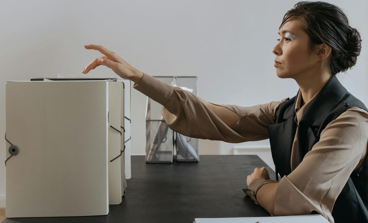 Mulher com expressão séria está organizando documentos em pastas após treinamento de cultura de responsabilização.