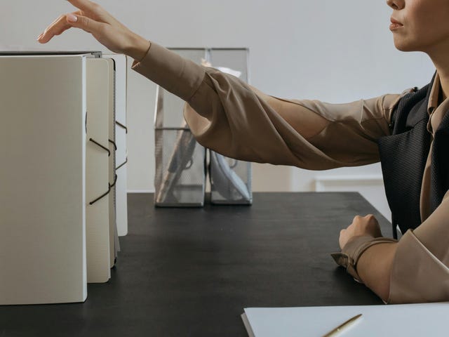 Mulher com expressão séria está organizando documentos em pastas após treinamento de cultura de responsabilização.