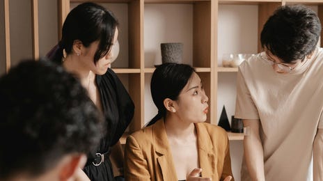 Equipe colaborativa sentada no escritório em uma grande mesa enquanto analisam documentos e conversam.