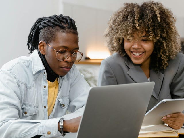 Duas pessoas conversando em frente a um computador sobre a importância do espanhol corporativo.