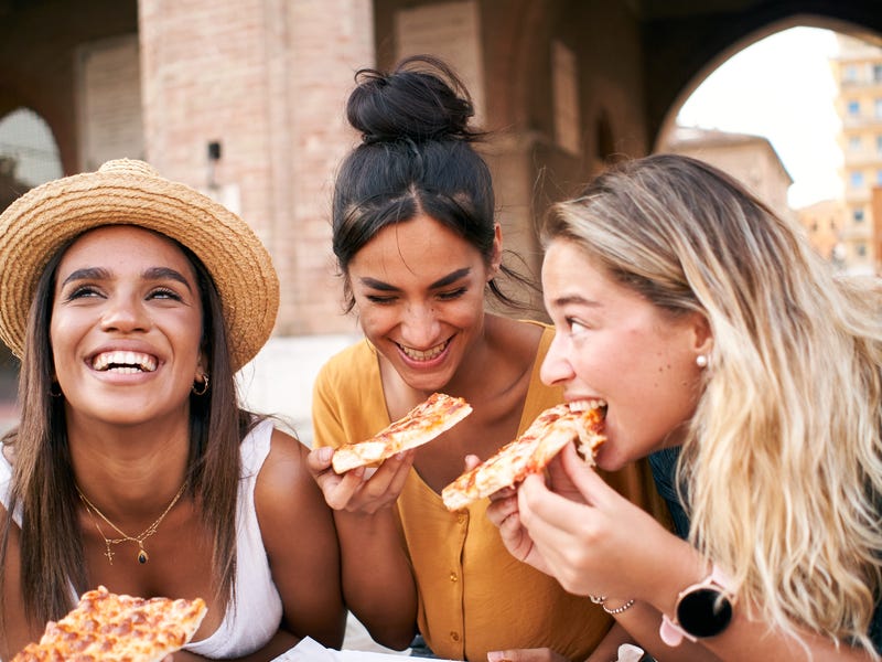 um grupo de amigas comendo pizza na Itália depois de aprender italiano