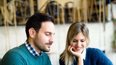 Um homem e uma mulher estudam juntos, por um tablet em uma cafeteria, para o exame Telc a2.