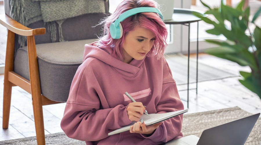 Mulher de cabelo rosa realizando uma lição de francês online.