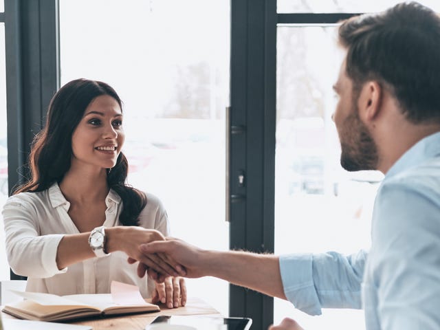 Homem e mulher dando um aperto de mão enquanto dizem olá em francês.