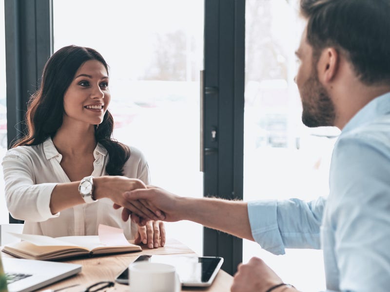 Homem e mulher dando um aperto de mão enquanto dizem olá em francês.