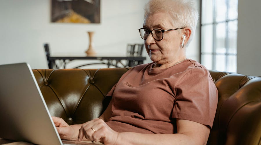 Mulher idosa estudando gramática do alemão em seu laptop.