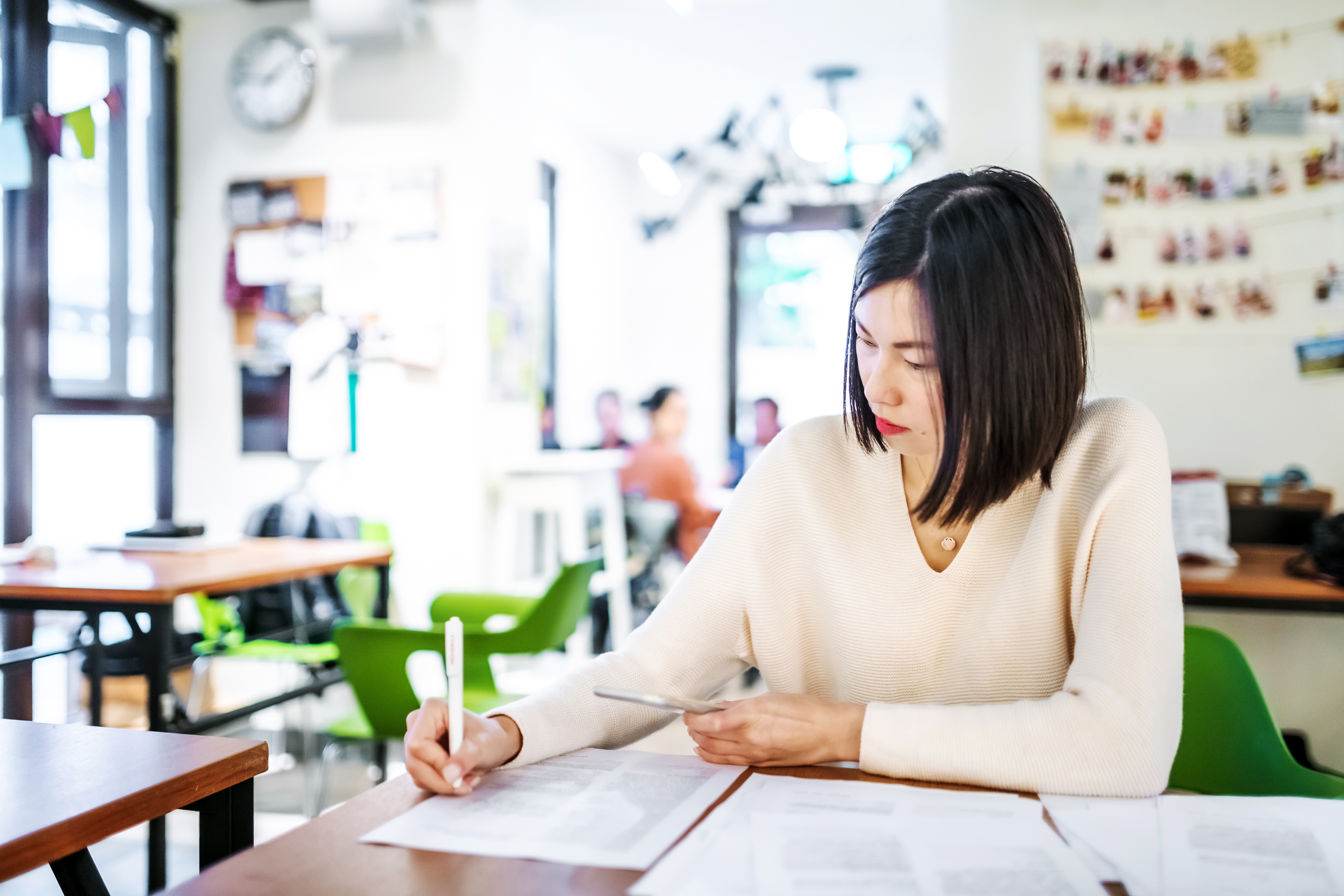 Mulher asiática escrevendo em um caderno.