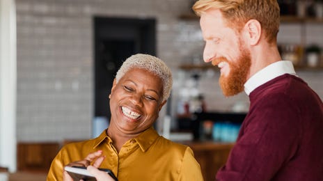 Mulher e homem rindo ao ver algo no celular.