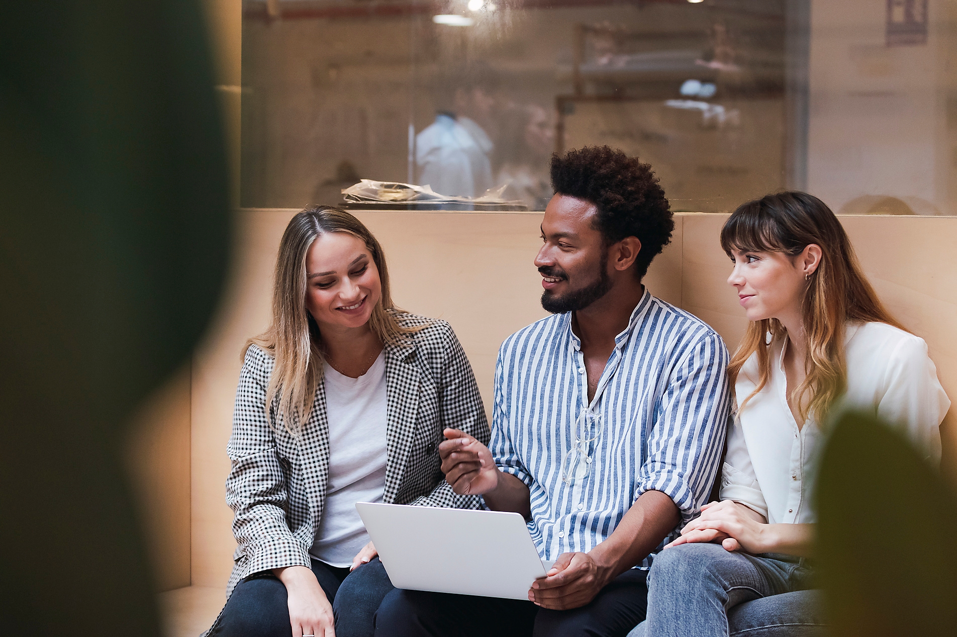 Um time de 3 pessoas, um rapaz e duas moças, que trabalham em uma empresa internacional, conversando em inglês.