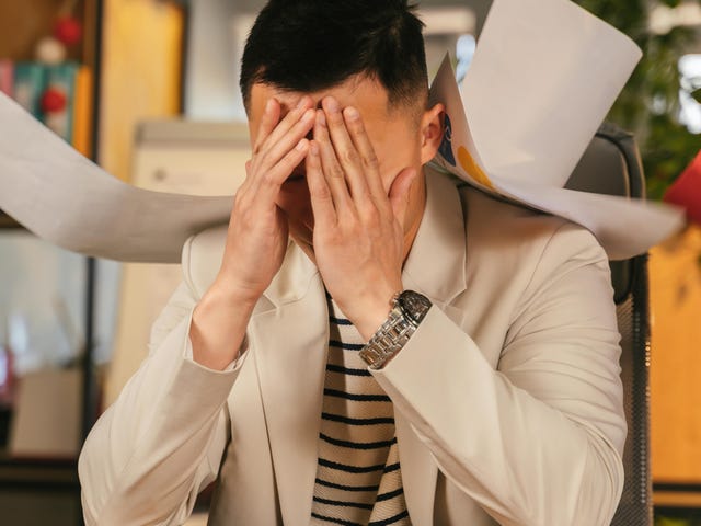 Homem estressado no trabalho com demandas infinitas, fazendo falta um treinamento de gestão de estresse.