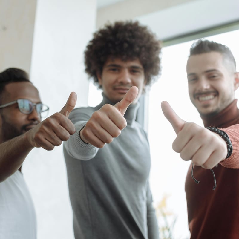 Colegas de trabalho fazendo sinal de joia com a mão para dizer "bom trabalho" em espanhol.