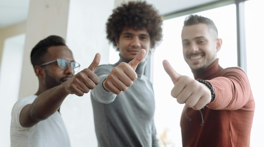 Colegas de trabalho fazendo sinal de joia com a mão para dizer "bom trabalho" em espanhol.