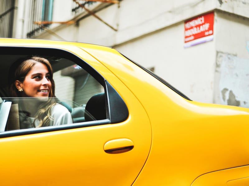 Mulher pensa em palavras bonitas em inglês dentro de táxi.