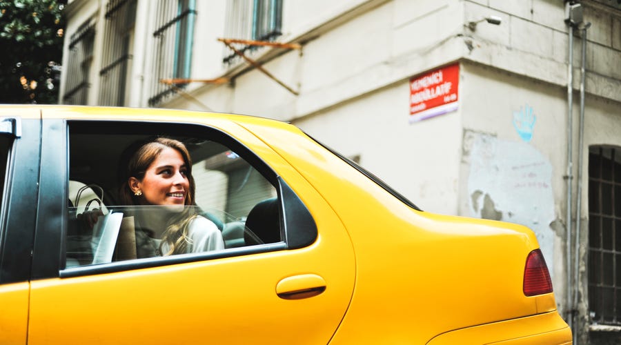 Mulher pensa em palavras bonitas em inglês dentro de táxi.