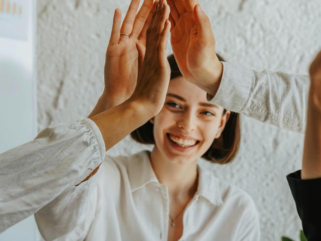 Mulher, que aprendeu sobre influência no trabalho, ganhou apoio dos colegas com um toque de mãos.