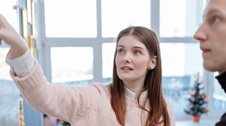 Dois alunos estudando inglês no Rio, em uma sala de aula com quadro branco.