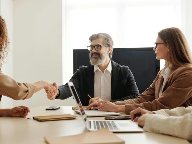 Homem em uma reunião com cliente em um aperto de mão com mulher da outra parte.