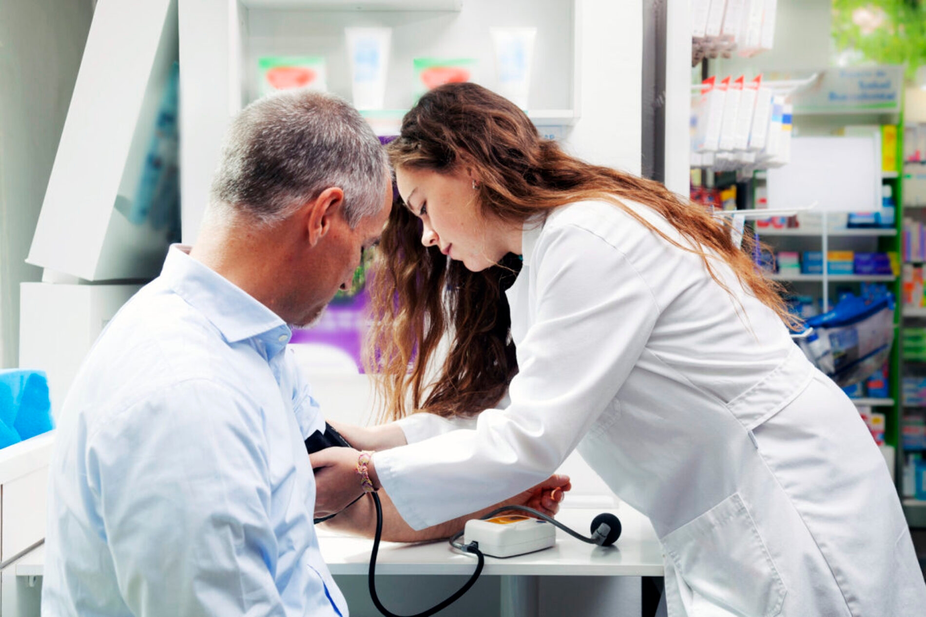 Homem conferindo a pressão enquanto pratica o vocabulário de farmácia em inglês com a atentende.
