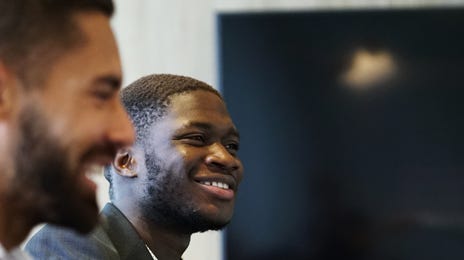Homem negro sorrindo durante uma reunião.