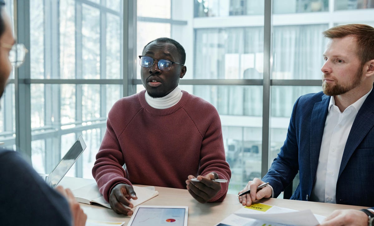 Homem se comunicando com o restante da equipe demonstrando suas habilidades profissionais aprendidas no curso de comunicação.