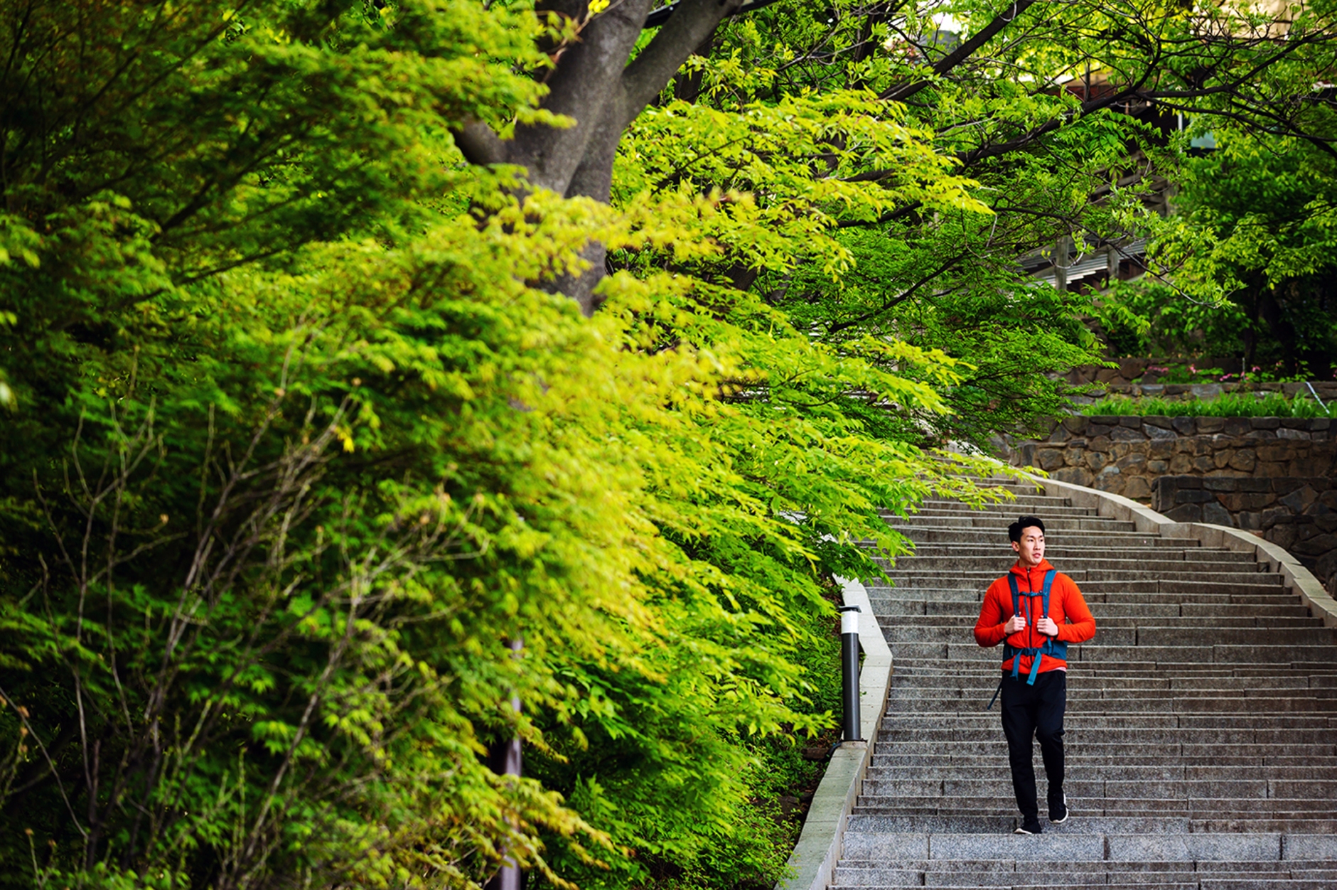 Homem mochileiro descendo escadas de um parque enquanto pensa em lugares em inglês.