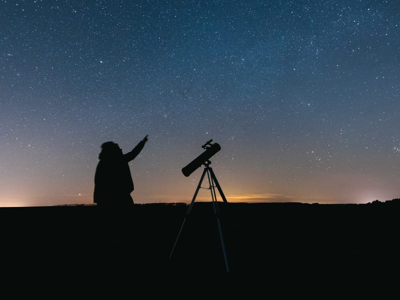 Homem observa céu estrelado com telescópio