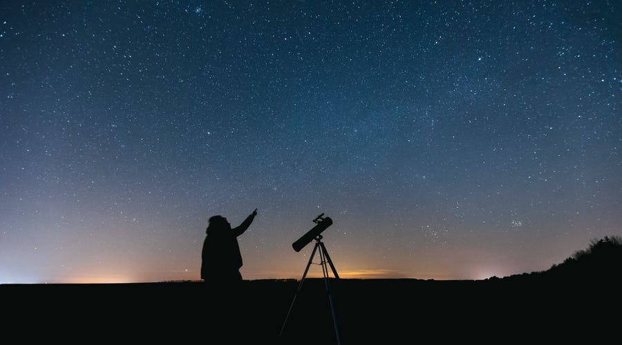 Homem observa céu estrelado com telescópio