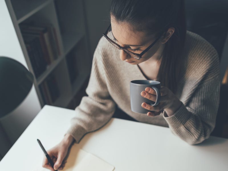 Mulher escrevendo palavras com todas as vogais.