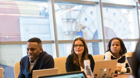 Colaboradores sentados em uma sala com uma mesa grande, descobrindo como organizar uma reunião com o workshop do Berlitz.