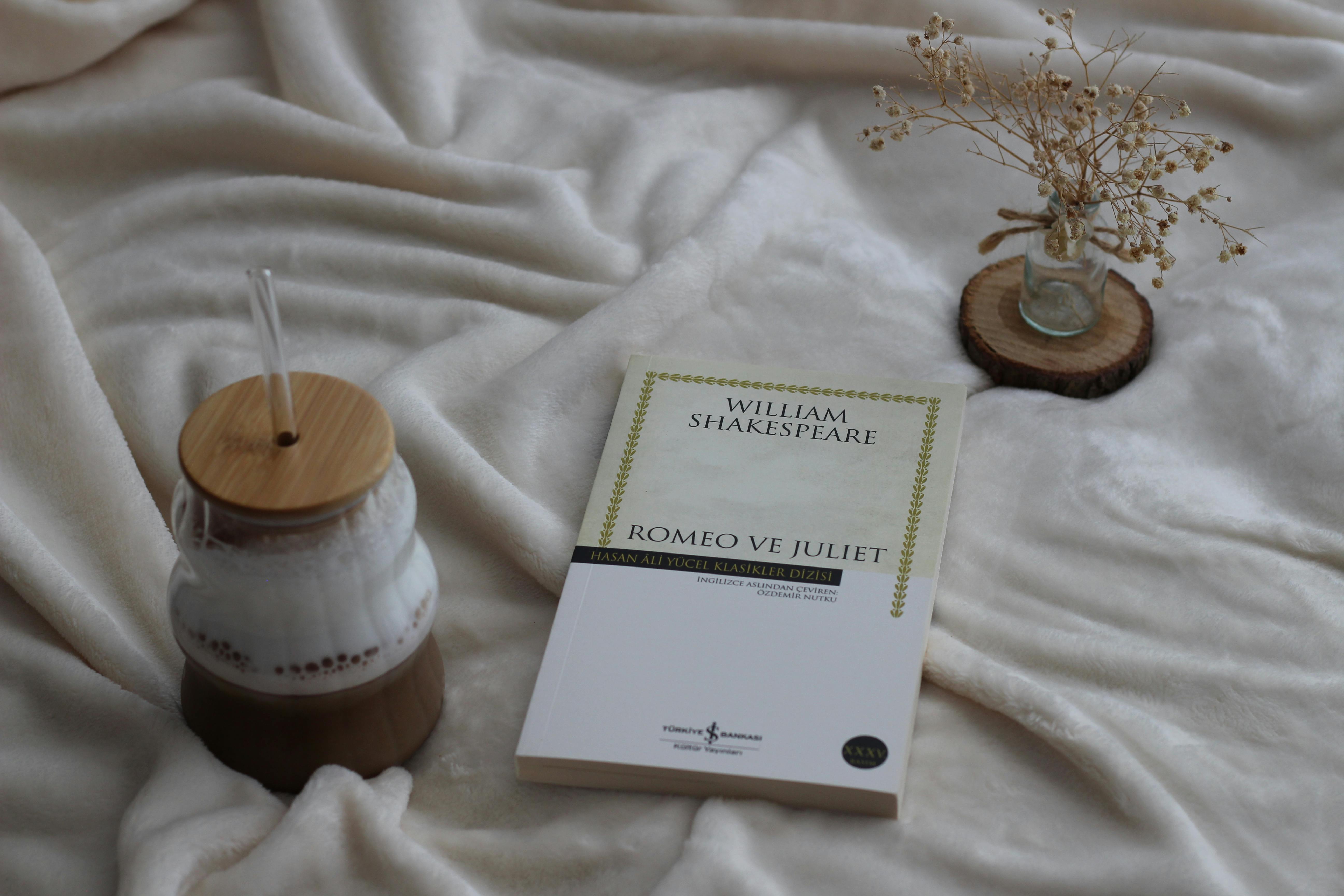 Livro "Romeo e Julieta" escrito em inglês sobre uma mesa com tecido branco aveludado.