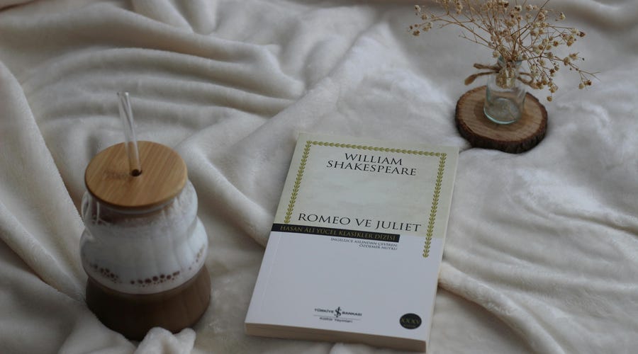 Livro "Romeo e Julieta" escrito em inglês sobre uma mesa com tecido branco aveludado.