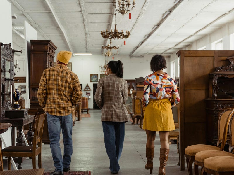 Três jovens em uma loja de furniture buscam uma nova mesa de jantar para a casa deles.