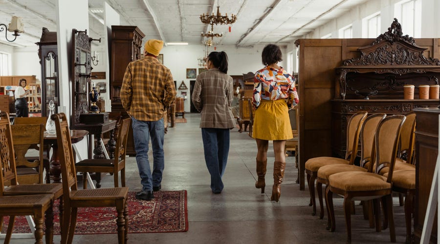 Três jovens em uma loja de furniture buscam uma nova mesa de jantar para a casa deles.