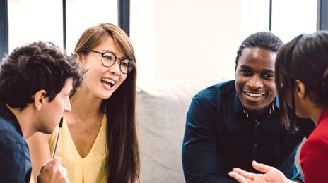 Grupo de pessoas conversando em ambiente de trabalho de forma descontraída.
