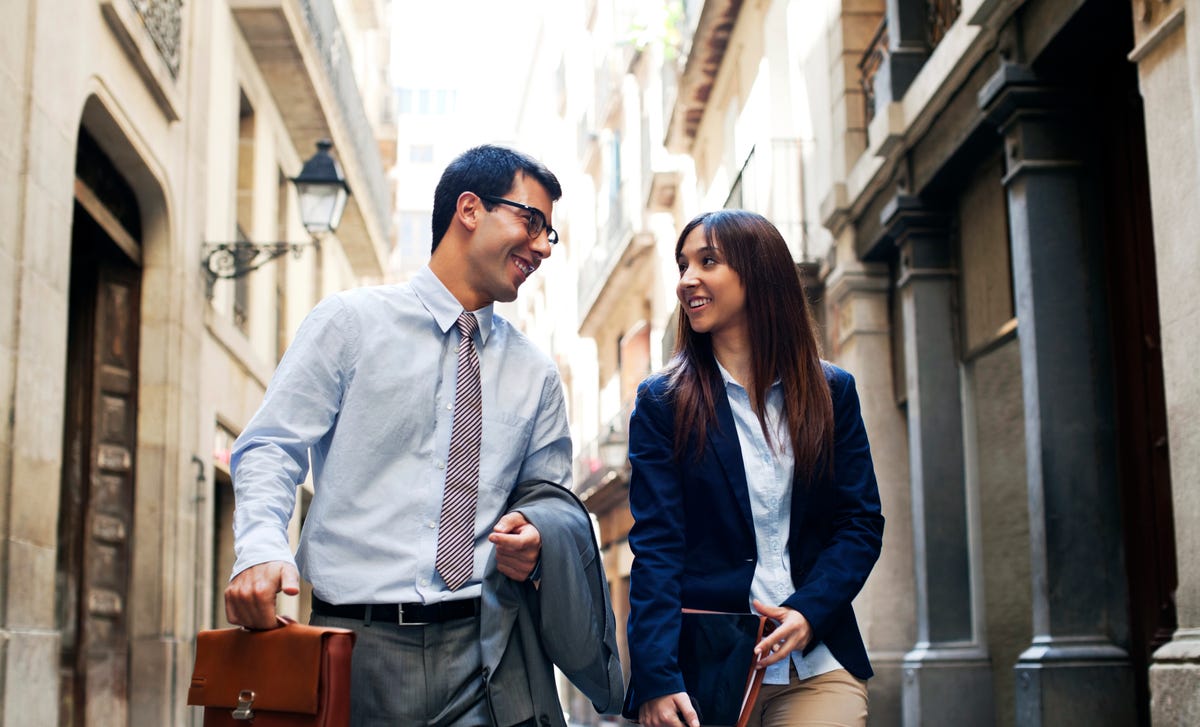 Funcionários que estudam um curso profissional de idiomas conversam sobre ele na saída do trabalho.