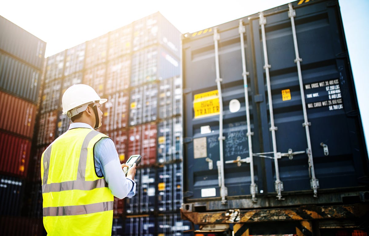 Fiscal de carga recebendo containers de mercadoria internacional após fazer um treinamento de inglês para área logística.