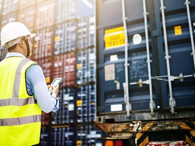 Fiscal de carga recebendo containers de mercadoria internacional após fazer um treinamento de inglês para área logística.