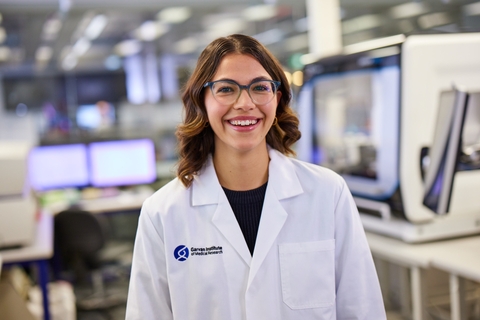 Female researcher with a lab coat in Garvan wearing glasses, she is smiling at the camera