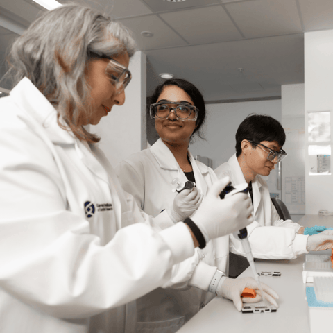 Three researchers working side by side at a lab bench.