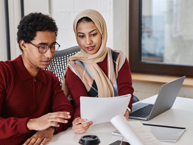 Student and instructor sitting in front of a laptop and checking a paper together during one of their language immersion classes