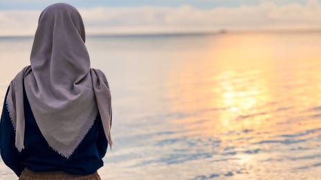 Woman in a scarf looking at the sea during her travels