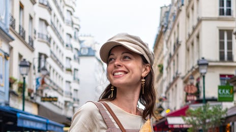 Woman holding a baguette and smiling while learning a language at language schools abroad