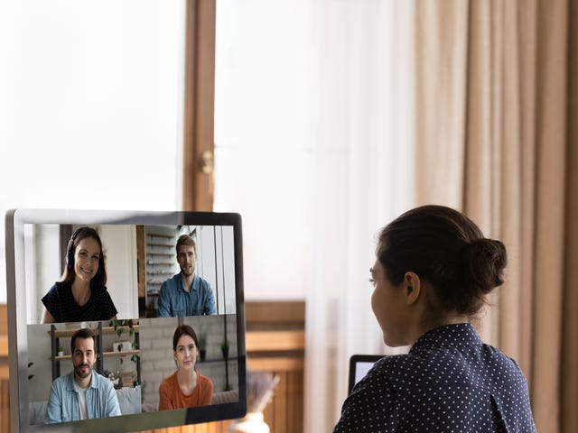 Woman sitting at her desk looking at her computer screen during one of her online group language classes